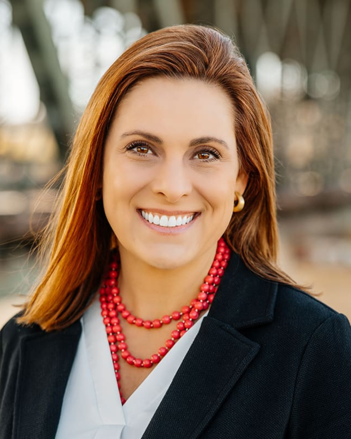 Dr. Kate Stanley pictured with a white blouse, black blazer, and a red beaded statement necklace